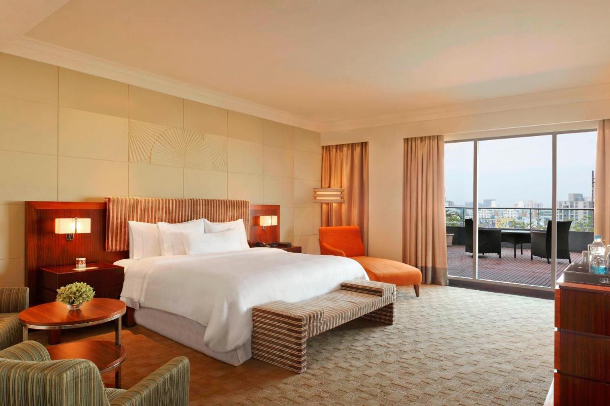 a hotel room with a large bed and a balcony at The Westin Pune Koregaon Park in Pune