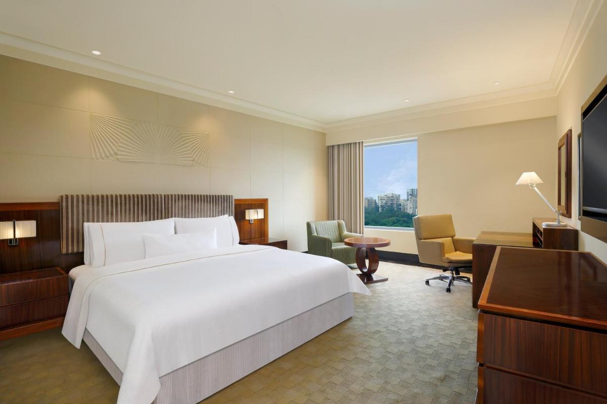 a hotel room with a large bed and a television at The Westin Pune Koregaon Park in Pune