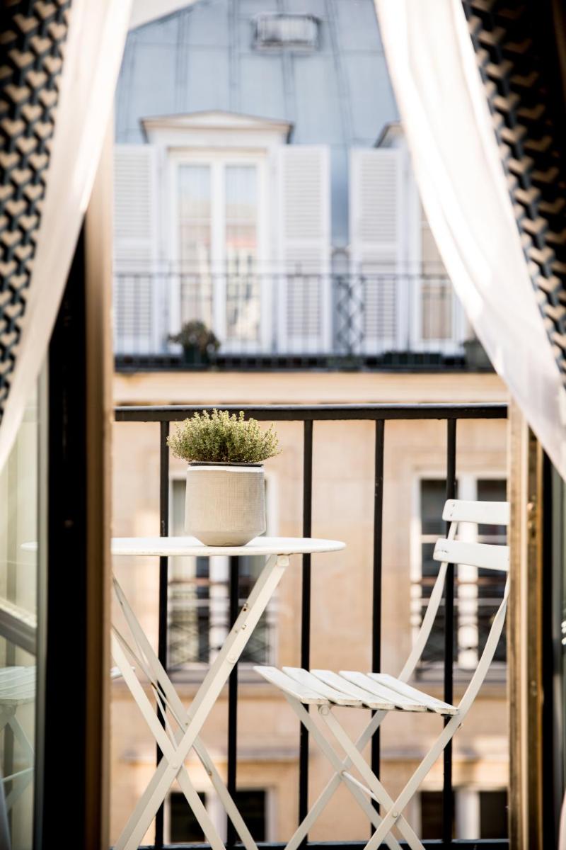 une table et des chaises sur un balcon avec une plante en pot dans l'établissement Renaissance Paris Vendome Hotel, à Paris