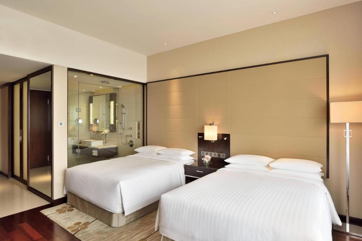 two beds in a hotel room with a bathroom at Kochi Marriott Hotel in Cochin