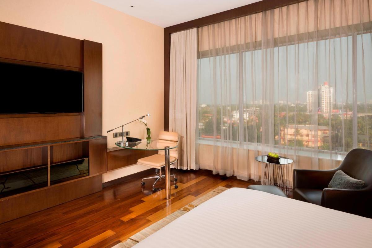 a hotel room with a television and a large window at Kochi Marriott Hotel in Cochin