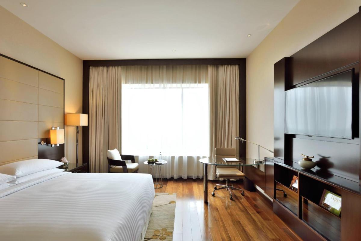 a bedroom with a bed and a desk and a window at Kochi Marriott Hotel in Cochin