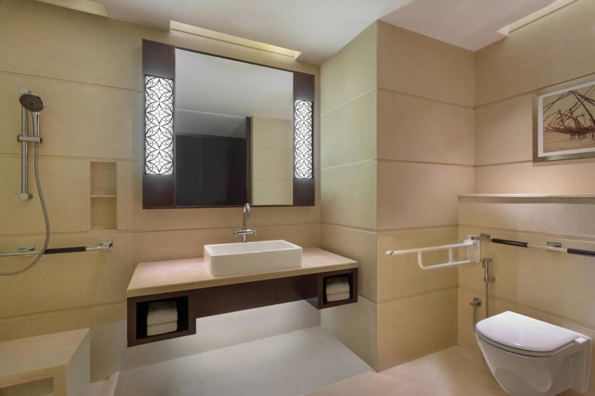 a bathroom with a sink and a toilet and a mirror at Kochi Marriott Hotel in Cochin