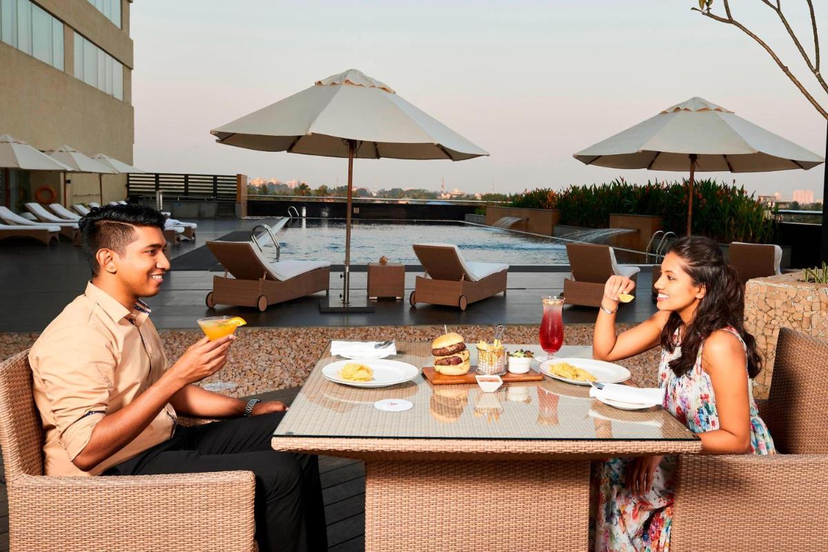 a man and woman sitting at a table on a patio at Kochi Marriott Hotel in Cochin