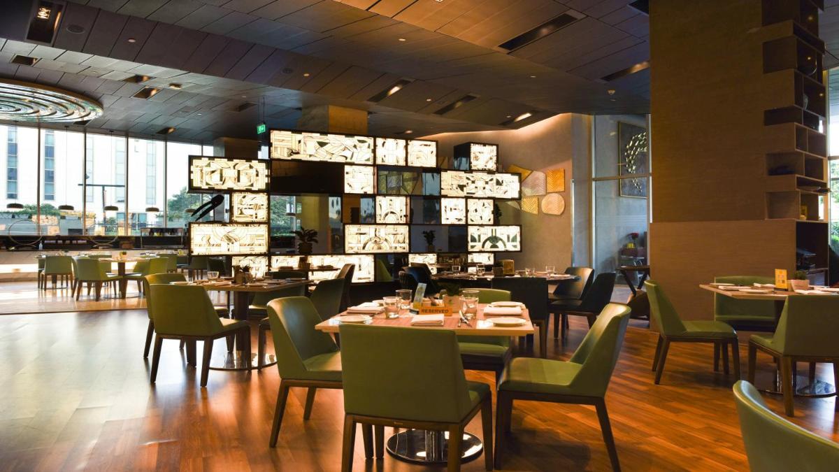 a dining room with tables and chairs in a restaurant at Holiday Inn New Delhi Aerocity by IHG in New Delhi