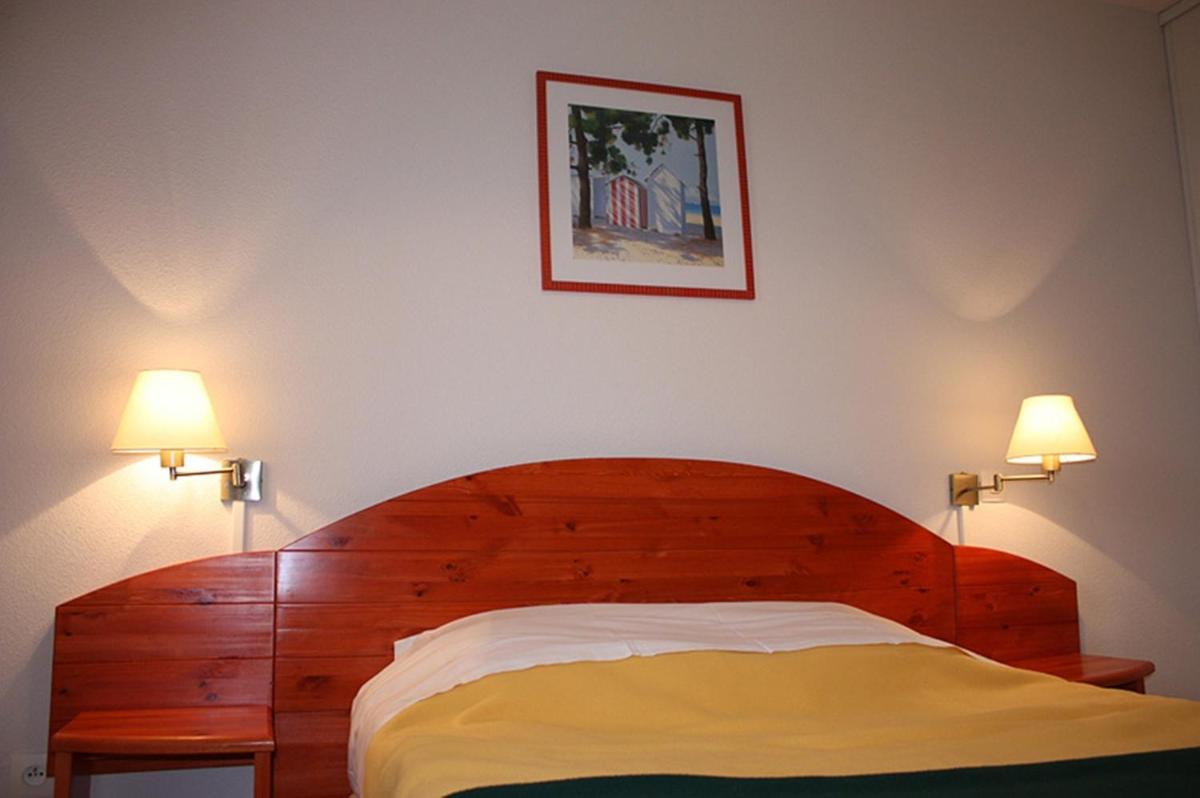 une chambre avec un lit en bois avec deux lampes dans l'établissement Résidence Goélia Le Cordouan, à Soulac-sur-Mer 12 autres photos