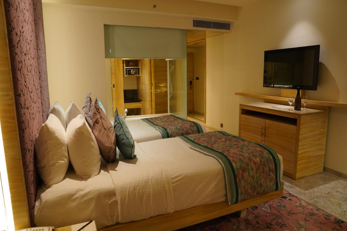 a bedroom with a bed and a flat screen tv at Hotel Royal Orchid Jaipur, Tonk Road in Jaipur