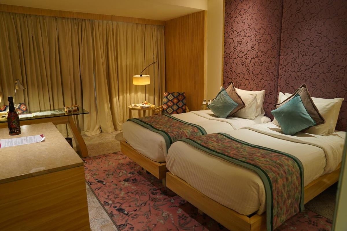 a hotel room with a large bed and a desk at Hotel Royal Orchid Jaipur, Tonk Road in Jaipur