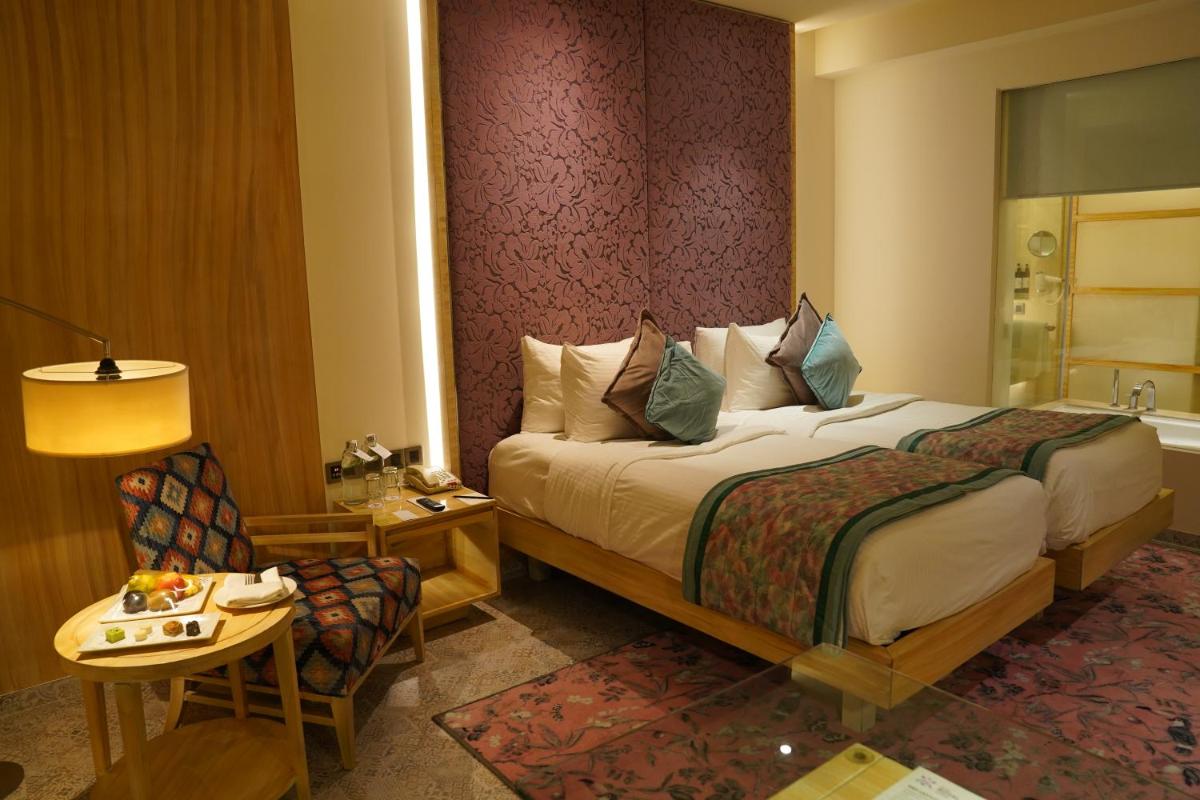 a hotel room with a bed and a table and a chair at Hotel Royal Orchid Jaipur, Tonk Road in Jaipur
