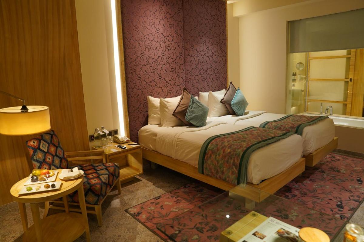 a hotel room with a bed and a table and a chair at Hotel Royal Orchid Jaipur, Tonk Road in Jaipur