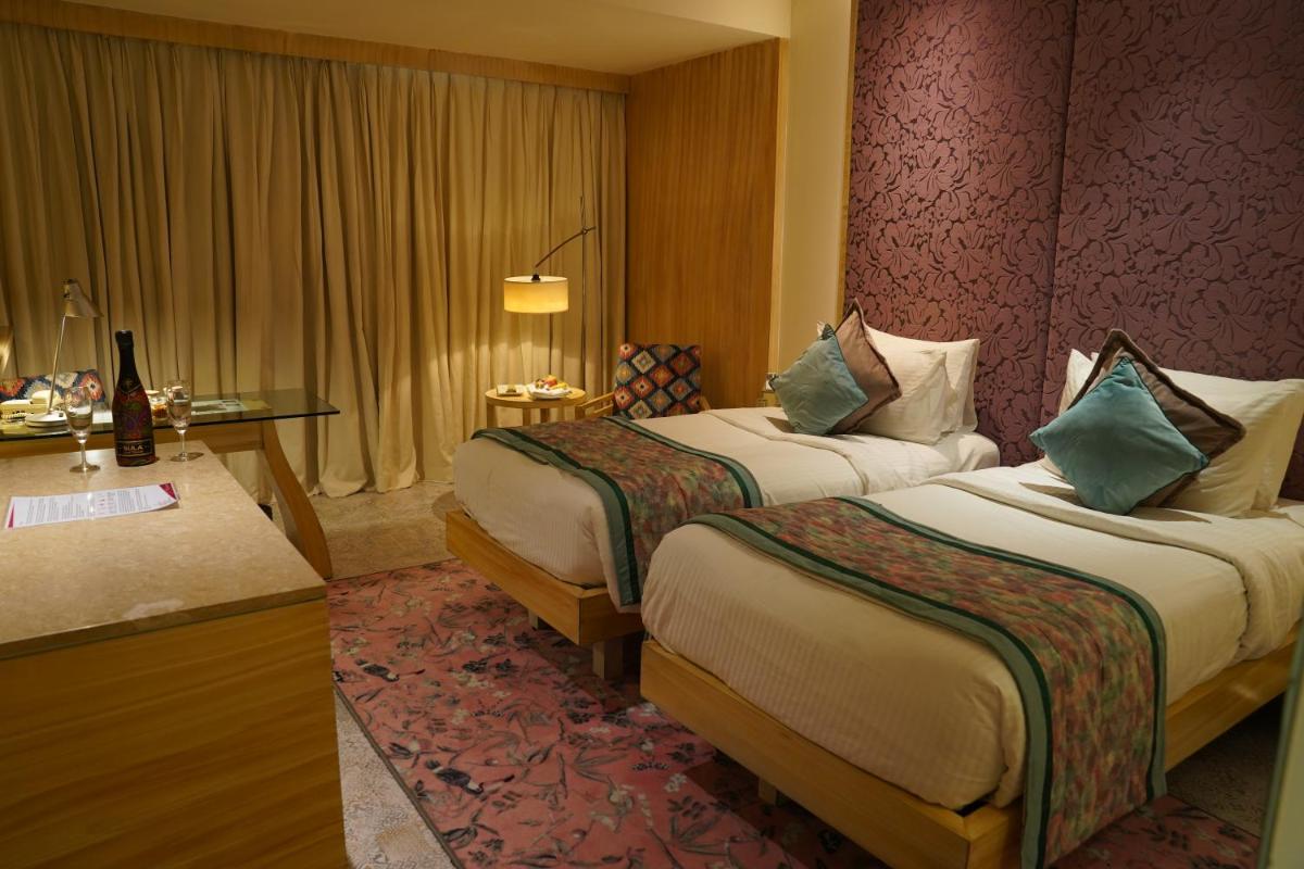 a hotel room with two beds and a desk at Hotel Royal Orchid Jaipur, Tonk Road in Jaipur