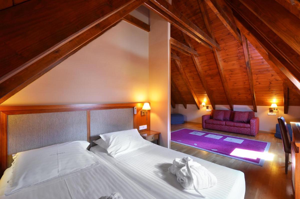 Un dormitorio con una cama blanca y una silla. en Hotel Spa Acevi Val d’Aran, en Vielha