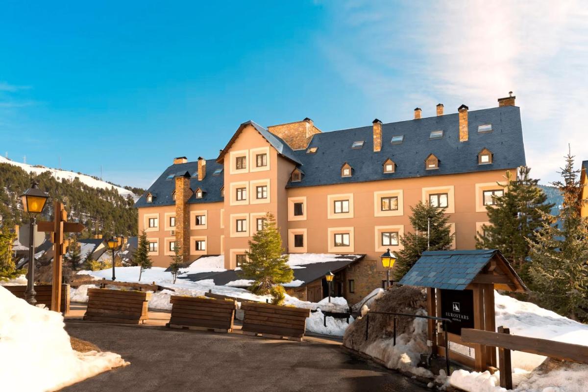 un gran edificio marrón con techo negro en la nieve en Eurostars Royal Tanau, en Baqueira Beret