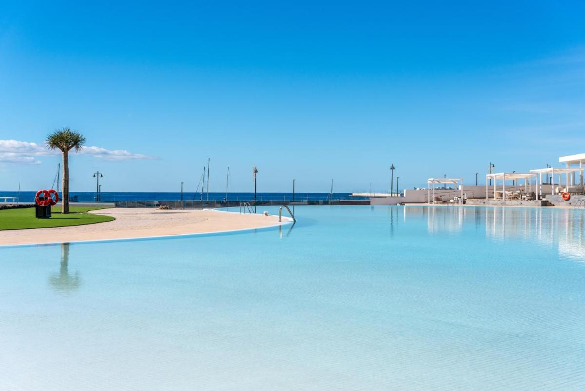 Una gran piscina de agua azul junto a una playa en Barceló Playa Blanca, en Playa Blanca