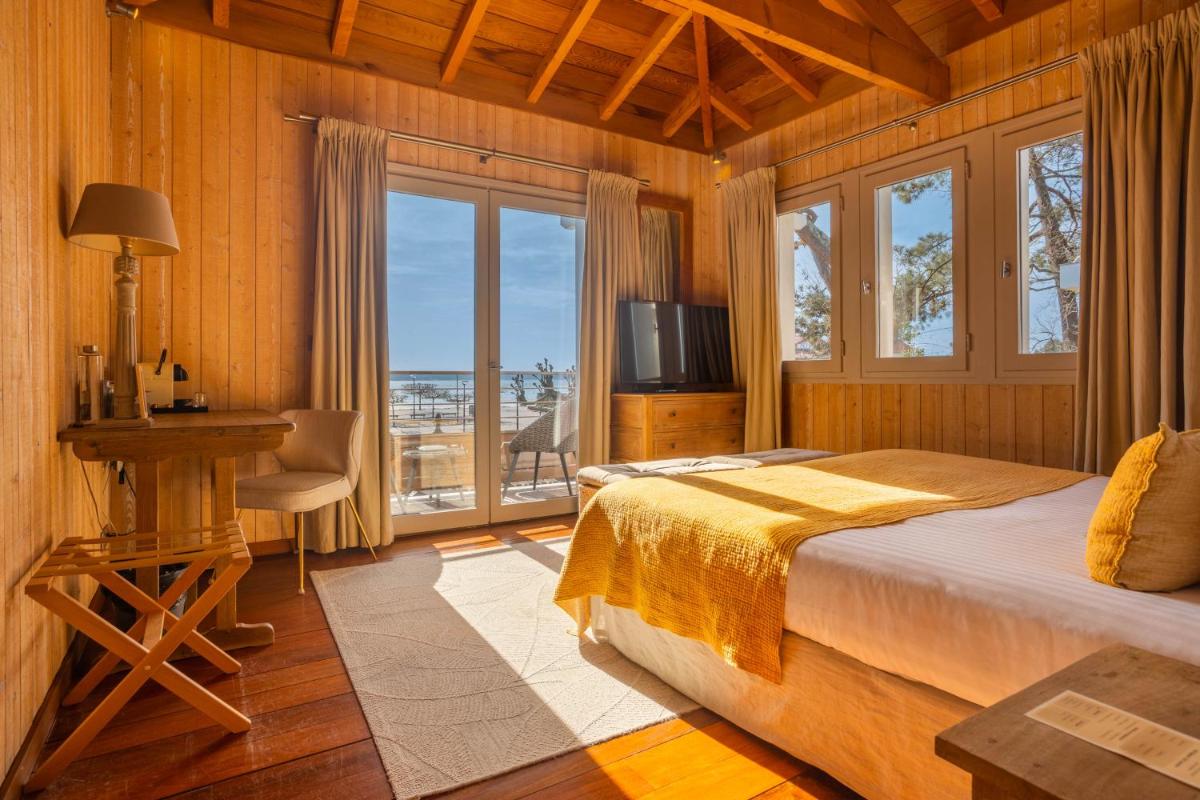 une chambre avec un lit, un bureau et une télévision dans l'établissement Hôtel Côté Sable, à Cap-Ferret