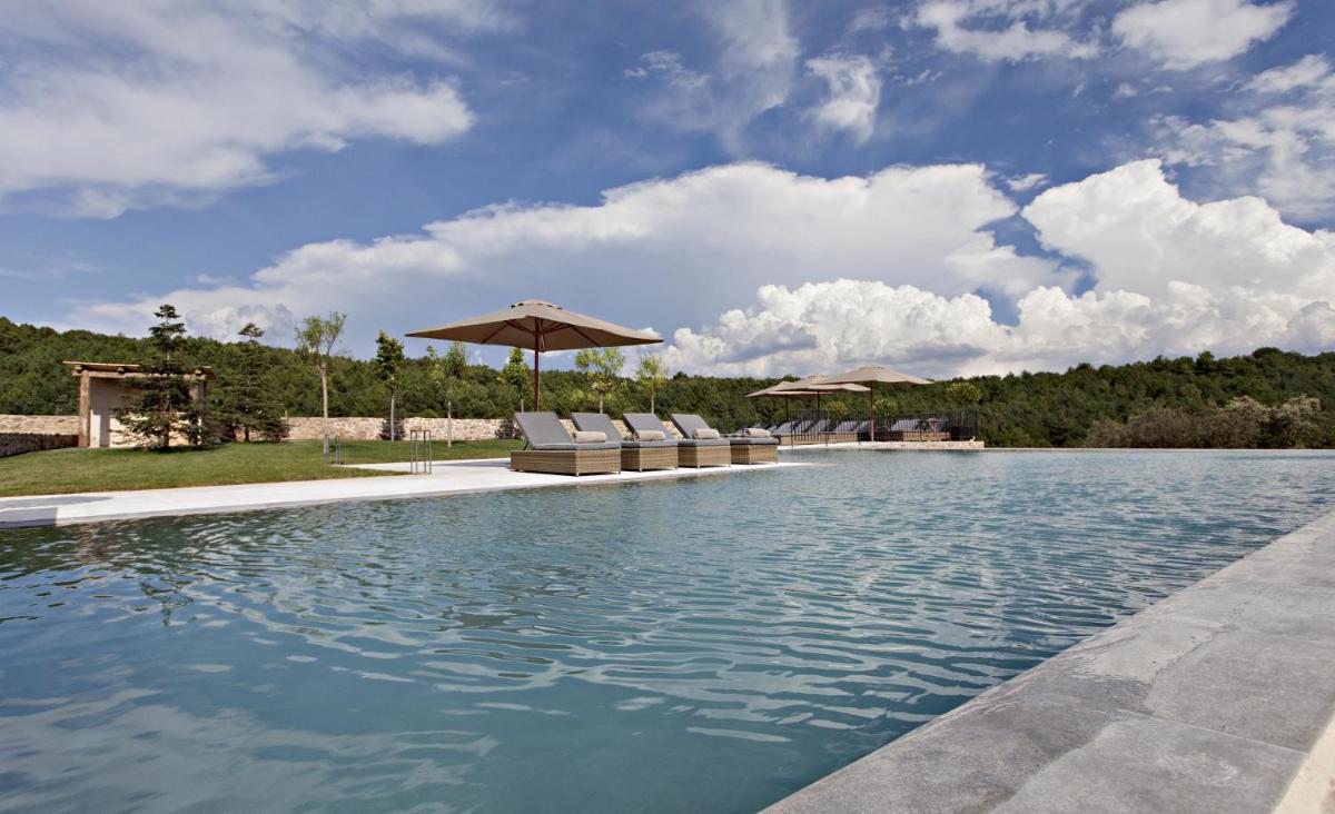 una piscina con sillas y sombrillas en un patio en La Vella Farga Hotel, en Lladurs