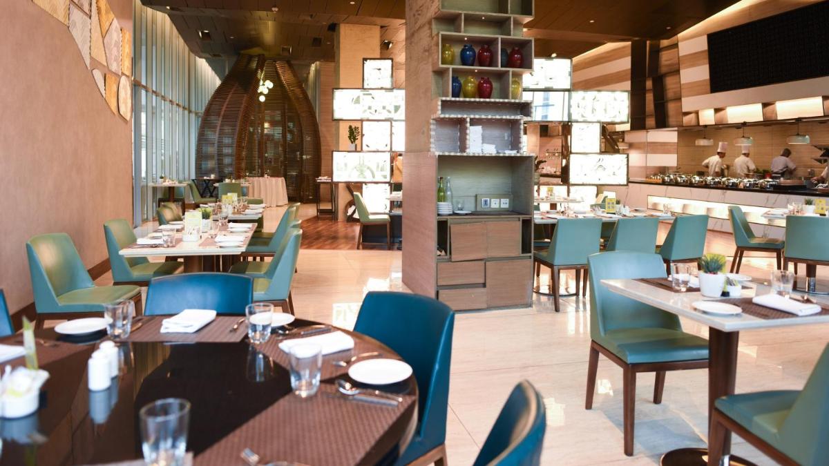 a dining room with tables and chairs and a restaurant at Holiday Inn New Delhi Aerocity by IHG in New Delhi
