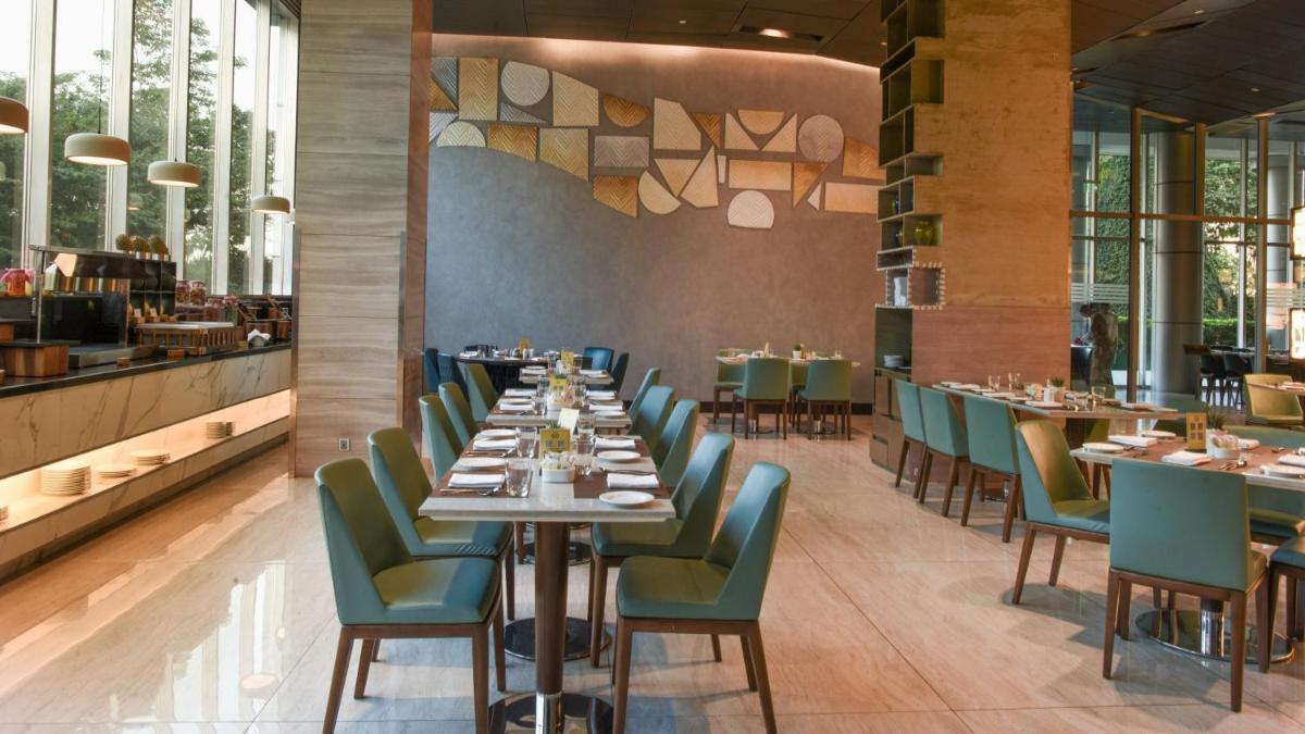 a dining room with tables and green chairs at Holiday Inn New Delhi Aerocity by IHG in New Delhi