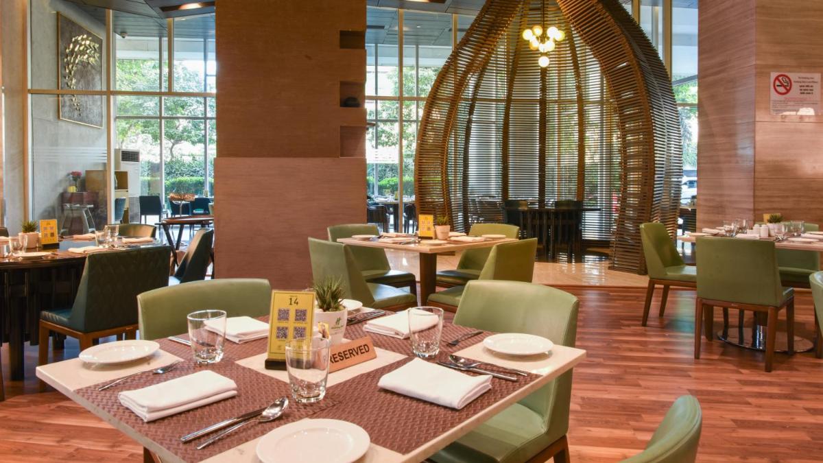 a dining room with tables and chairs in a restaurant at Holiday Inn New Delhi Aerocity by IHG in New Delhi