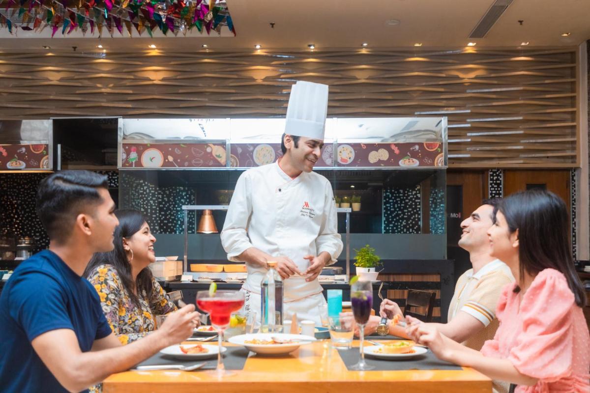 a group of people sitting around a table with a chef at Courtyard by Marriott Hyderabad in Hyderabad