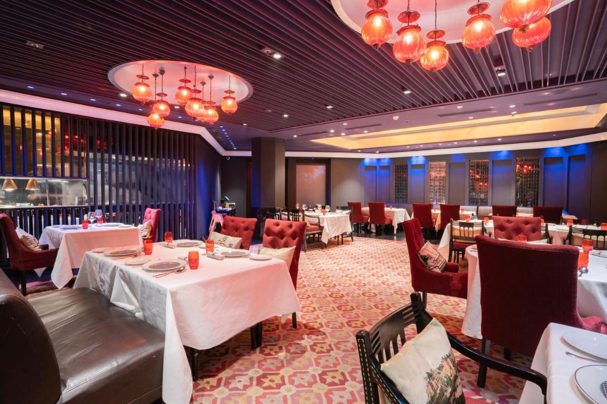 a dining room with tables and chairs and chandeliers at Hyderabad Marriott Hotel & Convention Centre in Hyderabad