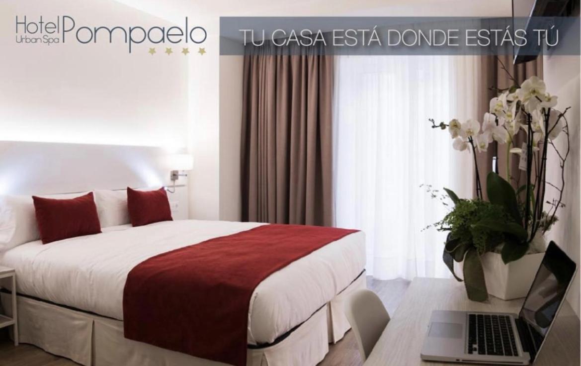 Un dormitorio con una cama y una computadora portátil en un escritorio. en Hotel Pompaelo Plaza del Ayuntamiento & Spa, en Pamplona