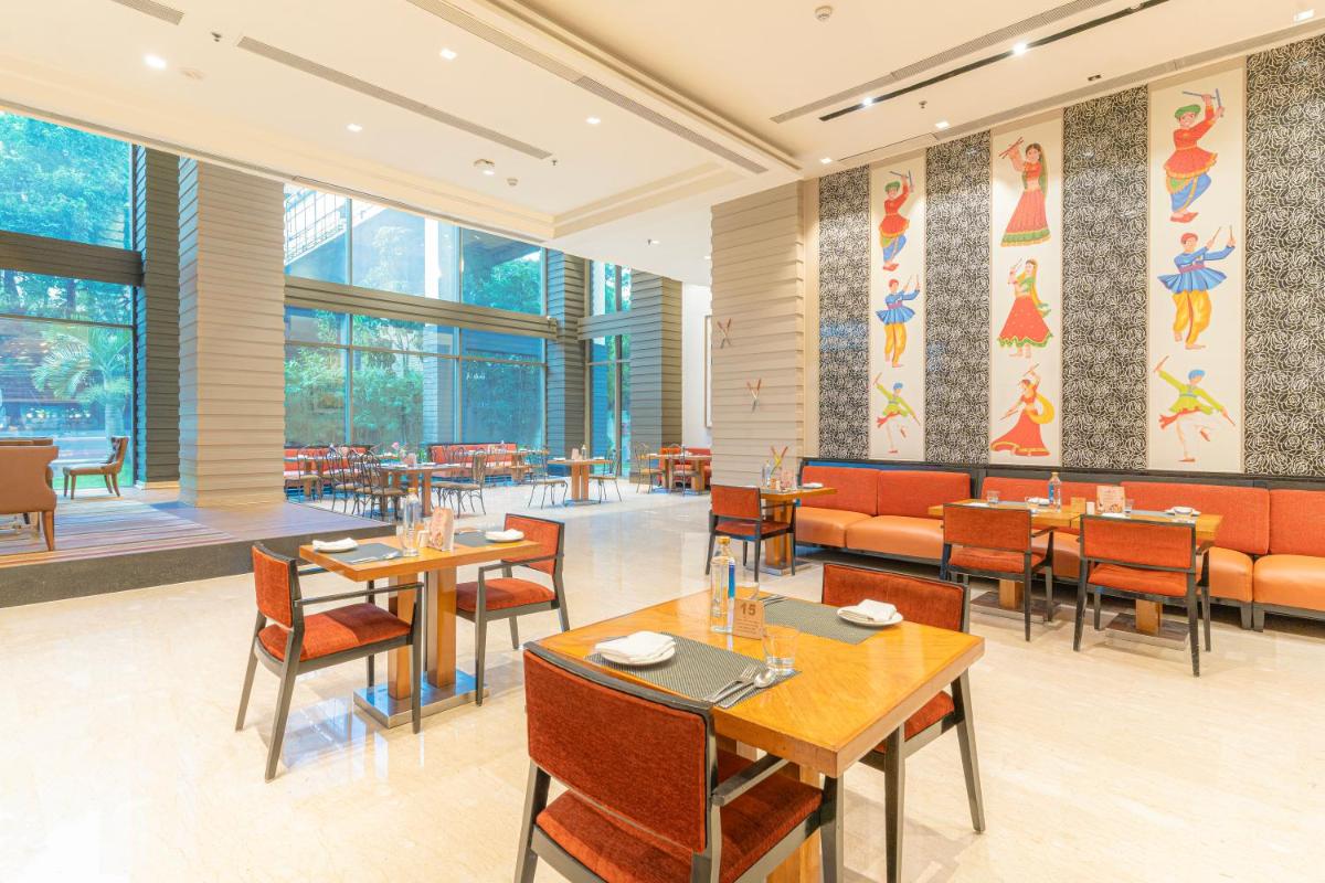 a restaurant with tables and chairs and windows at Courtyard by Marriott Hyderabad in Hyderabad a restaurant with tables and chairs and windows at Courtyard by Marriott Hyderabad in Hyderabad