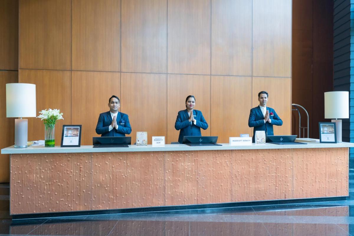 three people sitting at a counter in a lobby at Courtyard by Marriott Hyderabad in Hyderabad