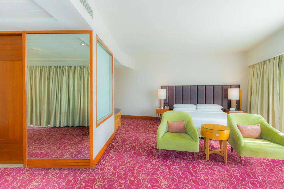 a bedroom with a bed and two chairs and a mirror at Courtyard by Marriott Hyderabad in Hyderabad