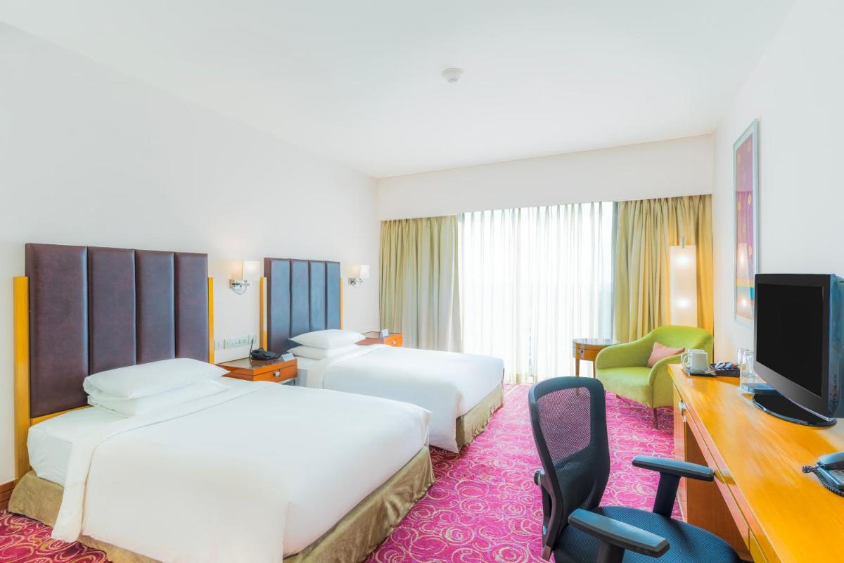 a hotel room with two beds and a television at Courtyard by Marriott Hyderabad in Hyderabad