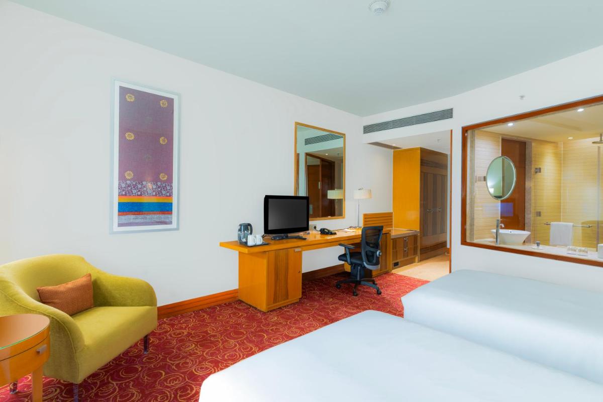 a hotel room with a bed and a desk with a computer at Courtyard by Marriott Hyderabad in Hyderabad