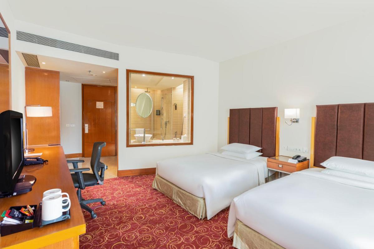 a hotel room with two beds and a television at Courtyard by Marriott Hyderabad in Hyderabad