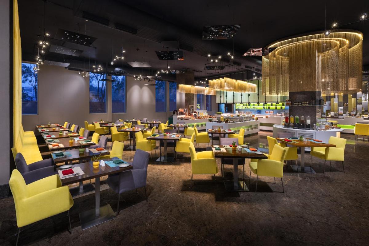 a dining room with tables and yellow chairs at Aloft Bengaluru Outer Ring Road in Bengaluru