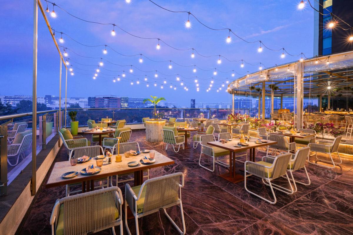 a restaurant on the roof of a building with tables and chairs at Aloft Bengaluru Outer Ring Road in Bengaluru