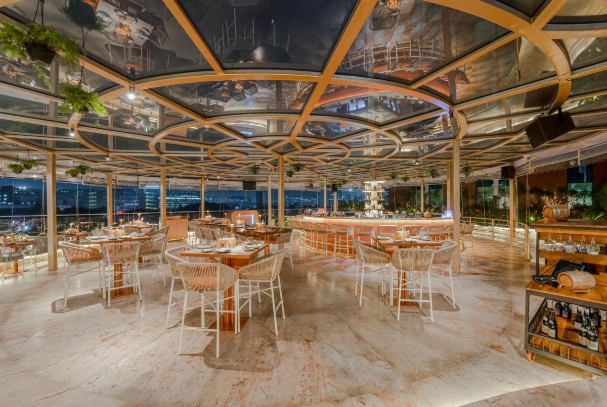 a restaurant with wooden ceilings and tables and chairs at Aloft Bengaluru Outer Ring Road in Bengaluru