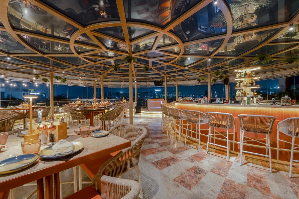a dining room with tables and chairs and a bar at Aloft Bengaluru Outer Ring Road in Bengaluru