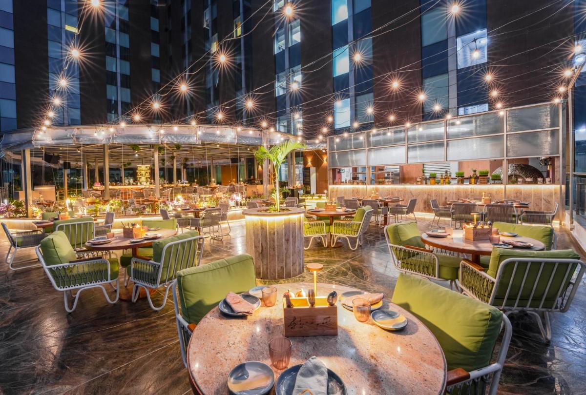 a restaurant with tables and chairs at night at Aloft Bengaluru Outer Ring Road in Bengaluru