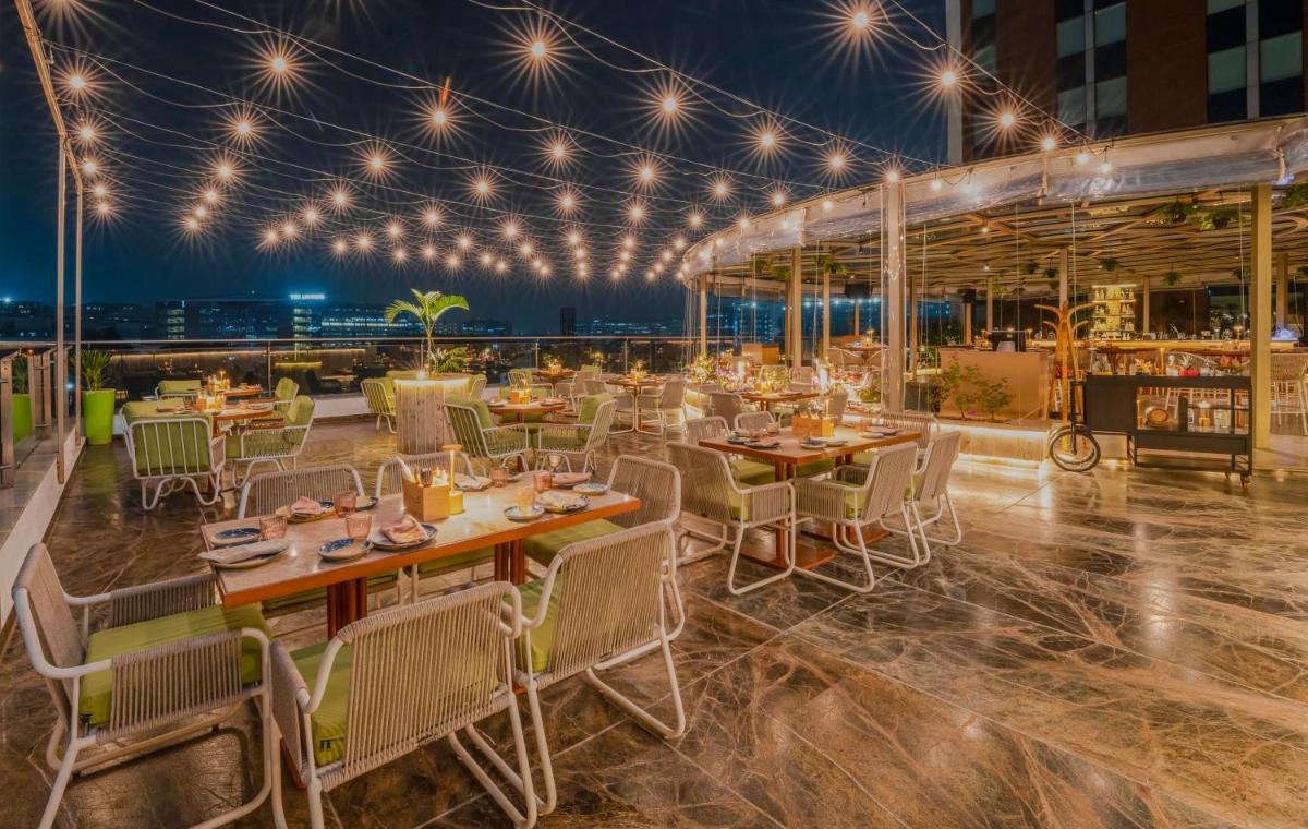a restaurant with tables and chairs on a rooftop at night at Aloft Bengaluru Outer Ring Road in Bengaluru