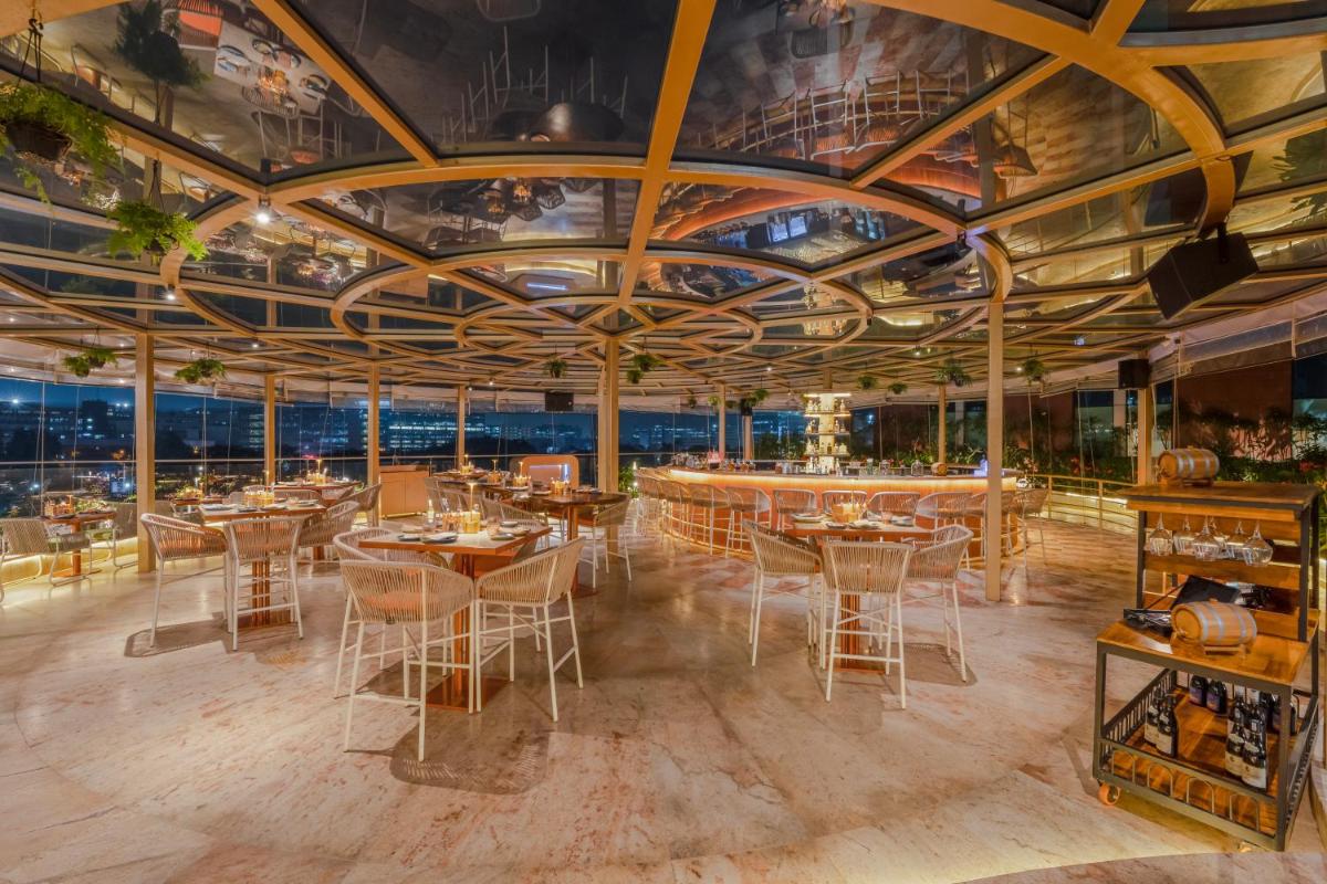 a dining room with tables and chairs and ceilings at Aloft Bengaluru Outer Ring Road in Bengaluru
