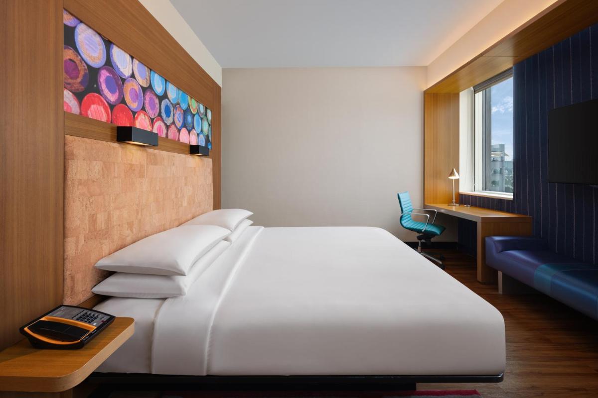 a bedroom with a large white bed and a desk at Aloft Bengaluru Outer Ring Road in Bengaluru