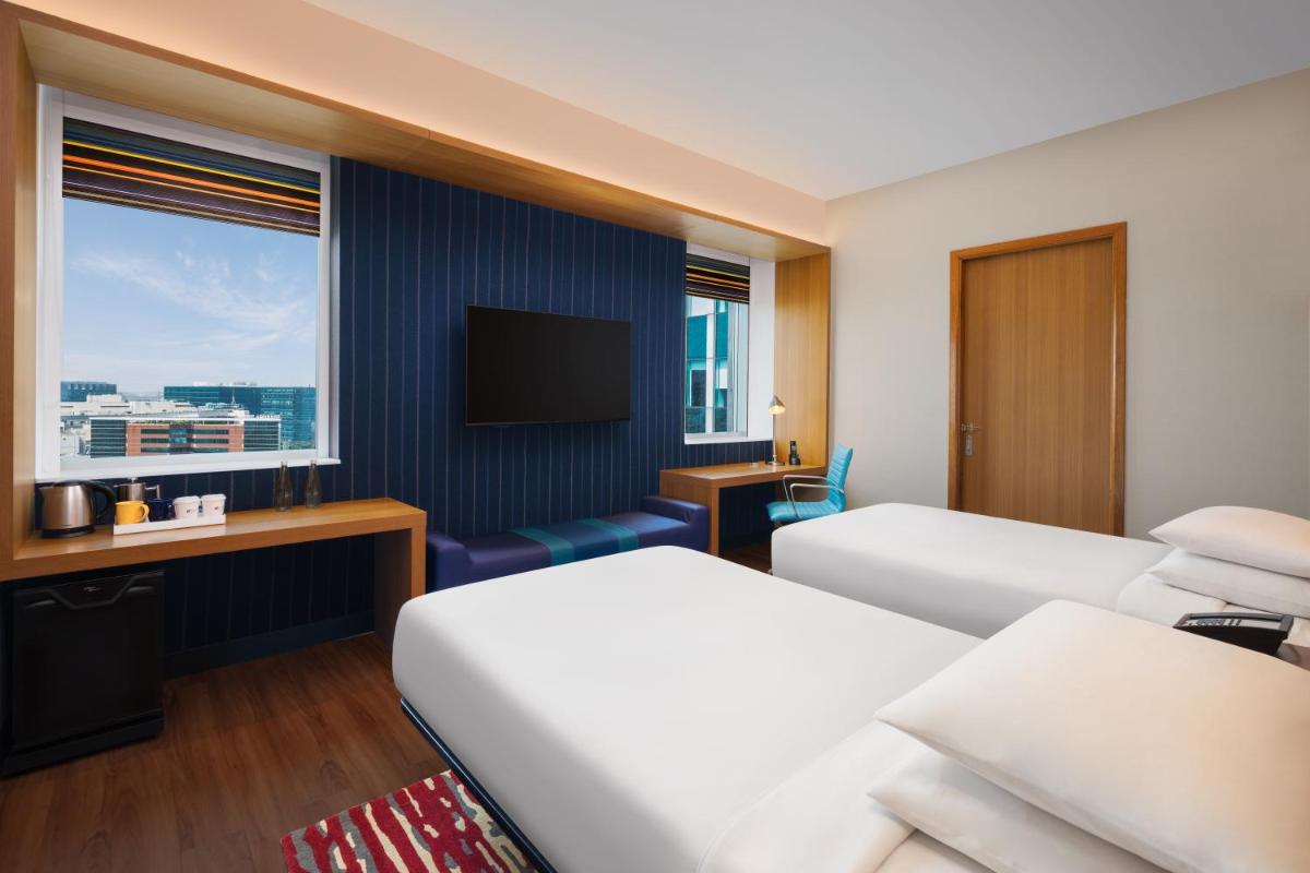 a hotel room with two beds and a television at Aloft Bengaluru Outer Ring Road in Bengaluru
