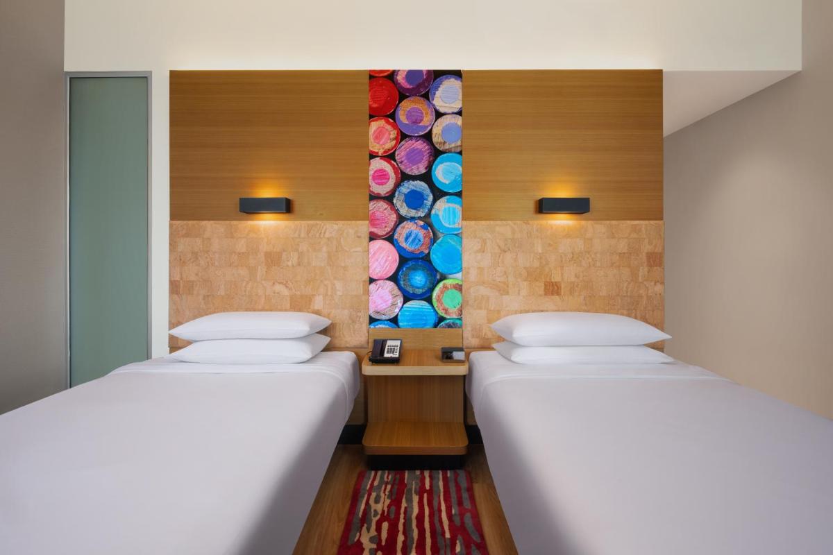 two beds in a room with a colorful tile wall at Aloft Bengaluru Outer Ring Road in Bengaluru