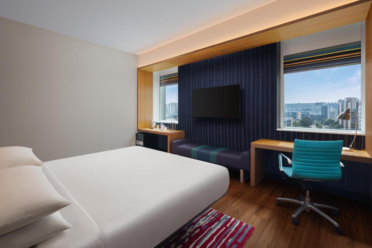 a bedroom with a bed and a desk and a television at Aloft Bengaluru Outer Ring Road in Bengaluru