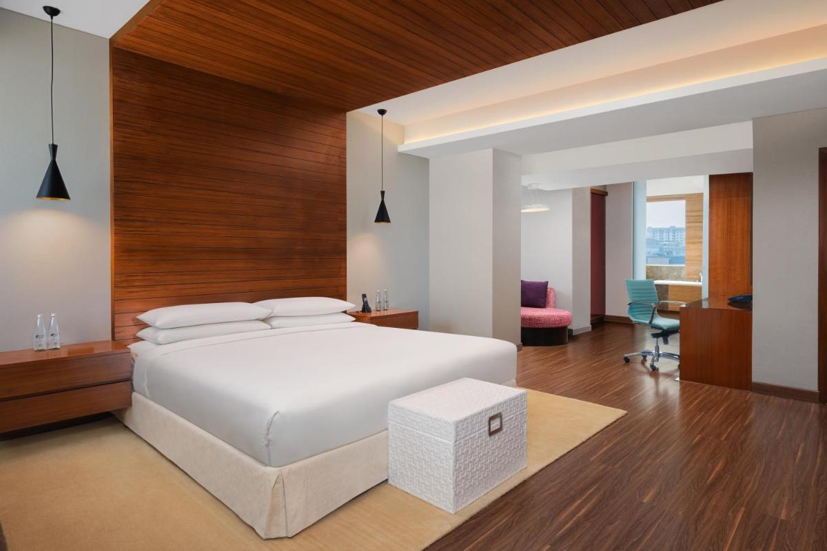 a bedroom with a white bed and a desk at Aloft Bengaluru Outer Ring Road in Bengaluru