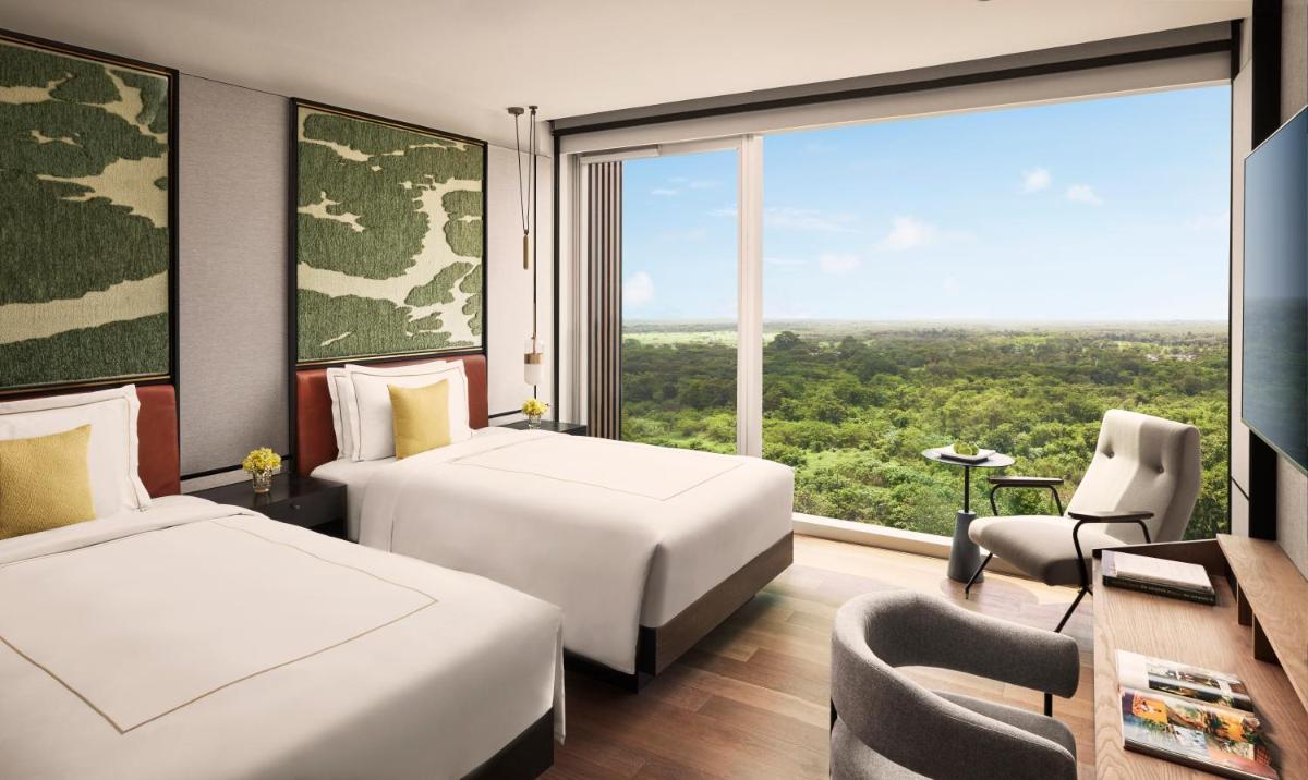 a hotel room with two beds and a large window at Taj The Trees, Mumbai in Mumbai