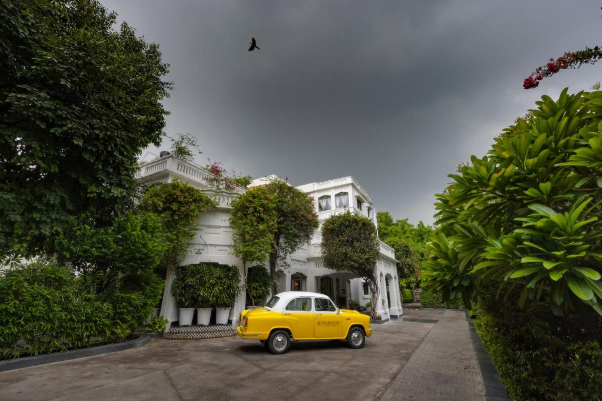 a yellow car parked in front of a white house at Saraca Hotel Lucknow in Lucknow