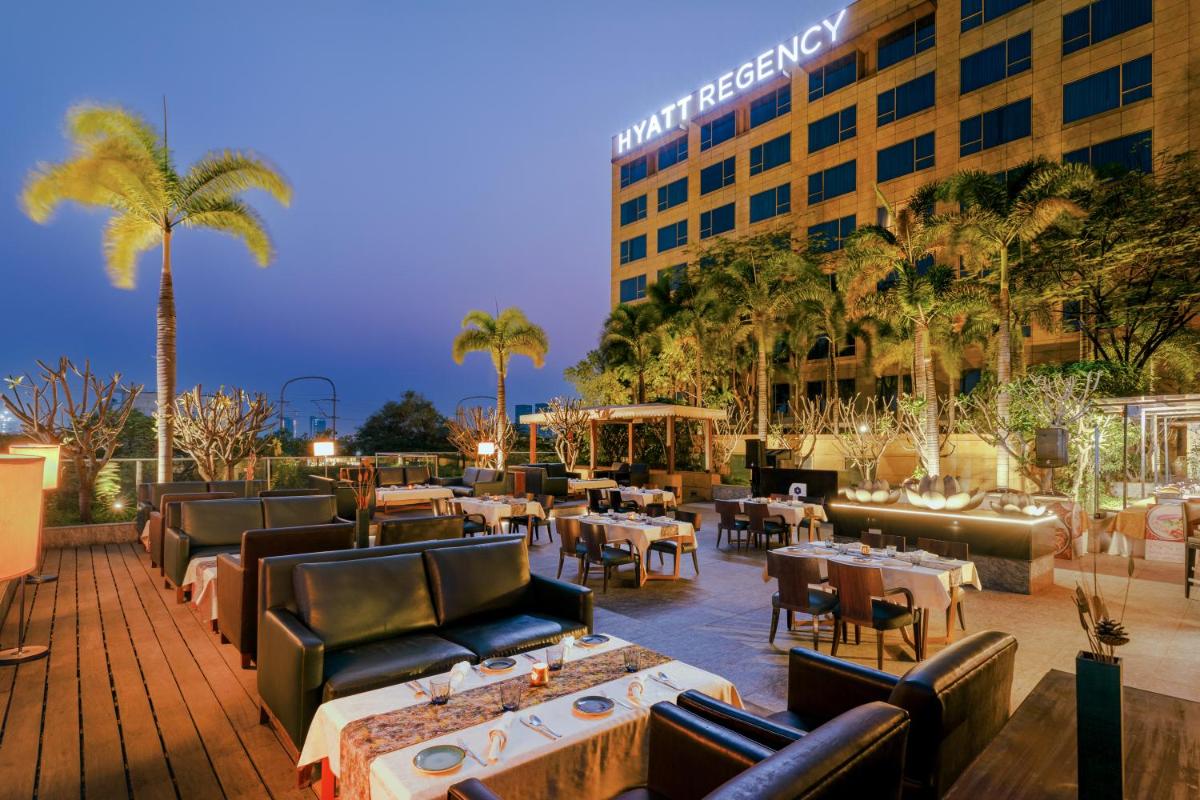 a patio with tables and chairs and a hotel at Hyatt Regency Pune Hotel & Residences in Pune a patio with tables and chairs and a hotel at Hyatt Regency Pune Hotel & Residences in Pune