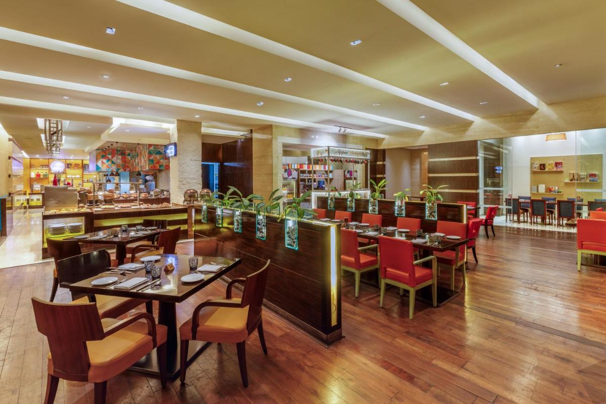 a restaurant with tables and chairs and a bar at Hyatt Regency Pune Hotel & Residences in Pune