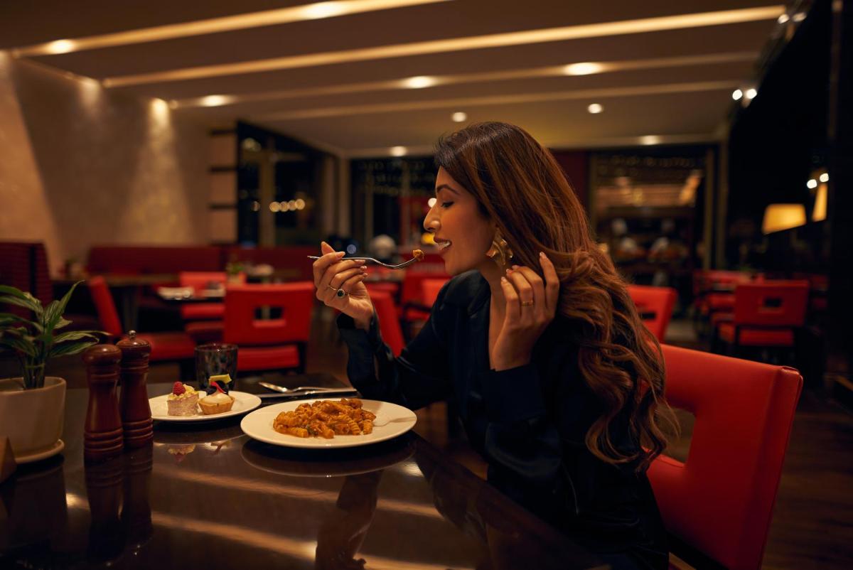 a woman sitting at a table eating food at Hyatt Regency Pune Hotel & Residences in Pune