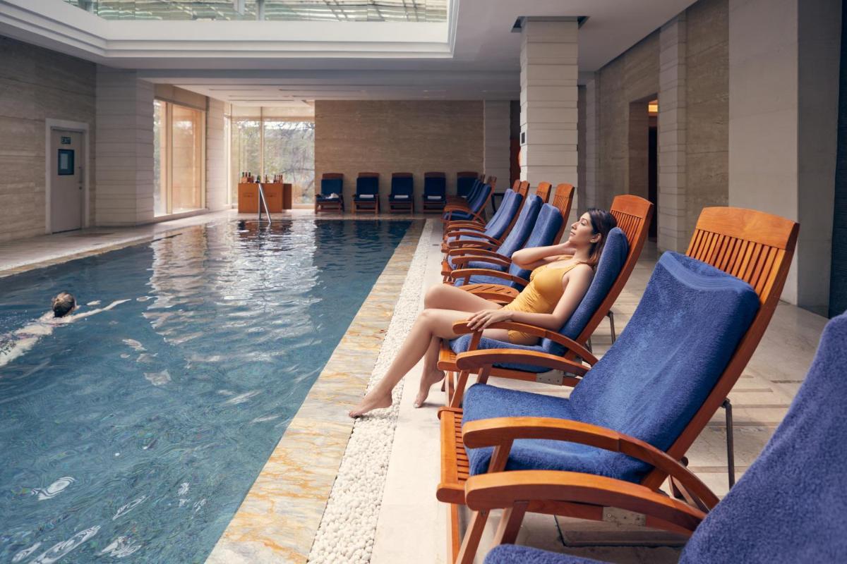 a woman sitting in chairs next to a swimming pool at Hyatt Regency Pune Hotel & Residences in Pune